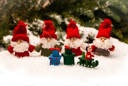 A group of four christmas dwarfs standing in the snow in front of the forestの写真素材
