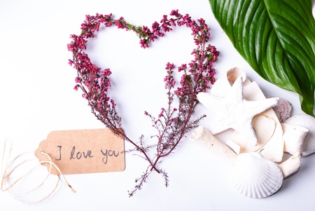 A set up of wellness items, a bamboo mat, a shell, candles, a branch, wood, a starfish and a sign saying "'I love you"の写真素材