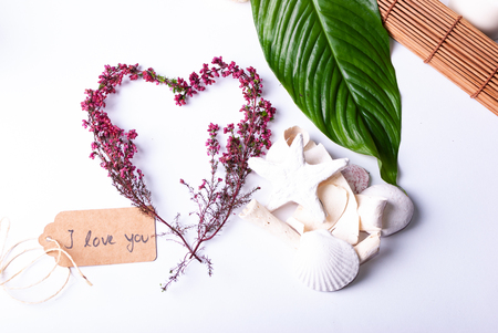 A set up of wellness items, a bamboo mat, a shell, candles, a branch, wood, a starfish and a sign saying "'Mother's Day" in Germanの写真素材