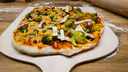 Angled view of a self made pizza on a pizza shovelの写真素材