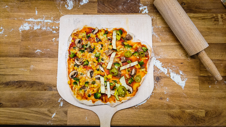 Top view of a self made pizza on a pizza shovelの写真素材