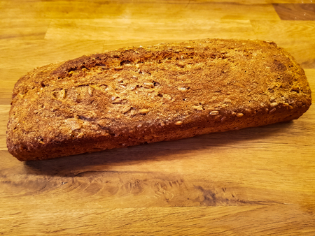A complete homemade whole grain bread loaf on a wooden tableの写真素材
