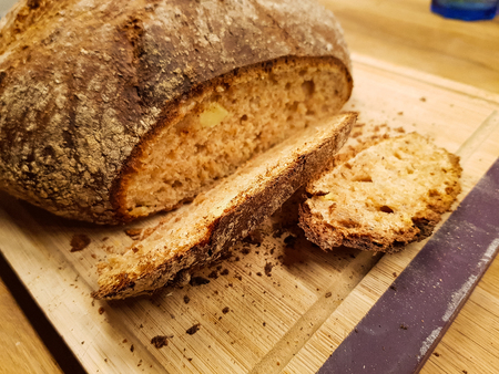 A sliced homemade whole grain bread loaf on a wooden table