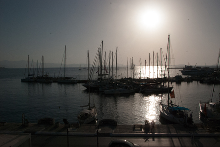 Silhouettes of sail boats in the ocean, the blue sky and the sun in the background - back lightの写真素材