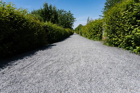 Low angle view of a long straight path with gravel in the sunlight - travel pathの写真素材