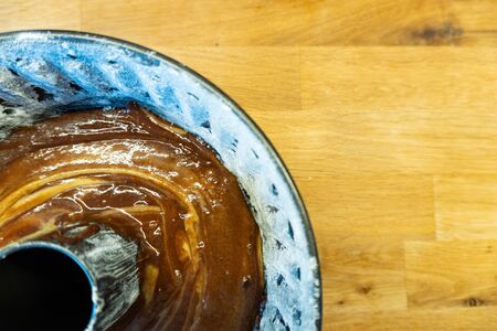 A cake form full of liquid chocolate cake before baking on a wooden table - top viewの写真素材