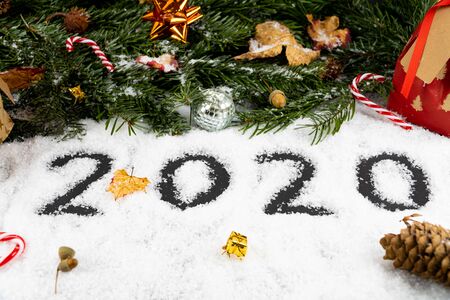 An arrangement with "2020" written in snow in the front, good wishes like peace, luck, love, joy and a happy new year besides. The back is decorated with fir trees, presents, sugar canesの写真素材