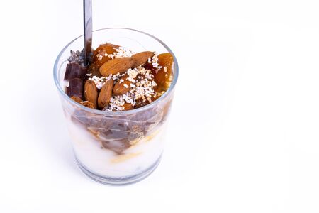 A vegan desert made of chia pudding, yoghurt, jam, fruit, cookies and almonds on white background - angled viewの写真素材