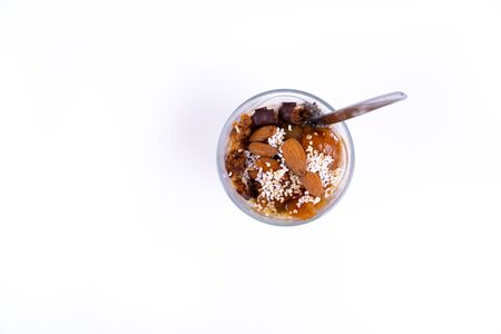 A vegan desert made of chia pudding, yoghurt, jam, fruit, cookies and almonds on white background - top viewの写真素材