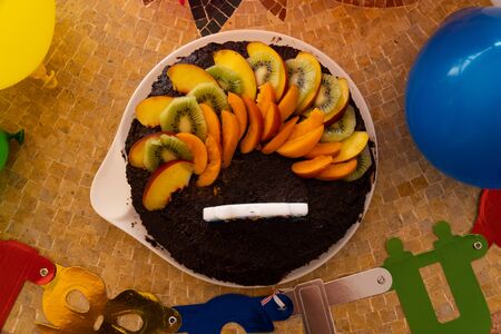A home made vegan chocolate cake with fresh fruit and a candle saying "Happy Birthday" - top viewの写真素材