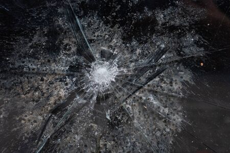 Cracks in a window glass coming from a bullet - close upの写真素材