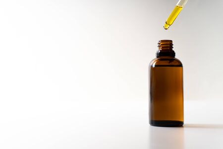 CBD oil or any other oil dropping into a small bottle - white background