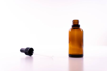 A small bottle with a dropper full of CBD oil or any other oil on white background - the dropper lying next to the bottleの写真素材