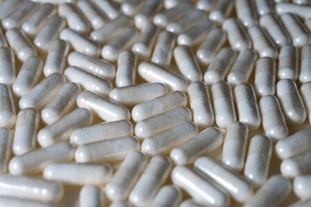 Close up of white medical pills or supplements on white background - angled view