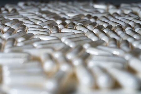 Close up of white medical pills or supplements on white background - angled view