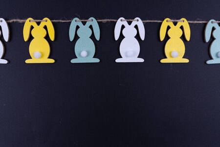 A row of colorful easter bunnies on black background with copy space