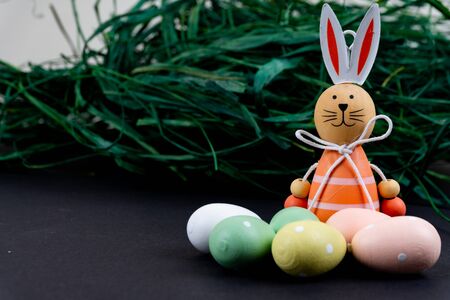 Close up of a few colorful easter eggs, a easter bunny and easter grass on black backgroundの写真素材