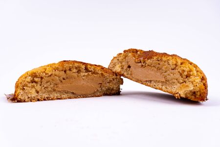 A cut cookie cake with peanut butter and caramel on white background with copy space - angled viewの写真素材