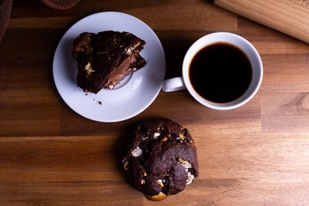 Delicious cookie cakes with chocolate with a cup of coffee on a wooden board with copy spaceの写真素材
