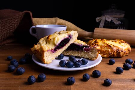 Delicious cheesecake cookie cakes with blueberries and a cup of coffee on a wooden board with copy spaceの写真素材