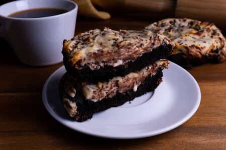 Delicious cookie cakes with chocolate and cheesecake with a cup of coffee on a wooden board with copy spaceの写真素材