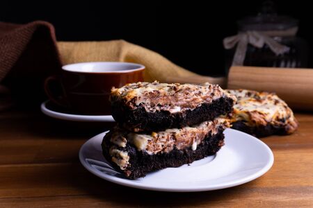Delicious cookie cakes with chocolate and cheesecake with a cup of coffee on a wooden board with copy spaceの写真素材