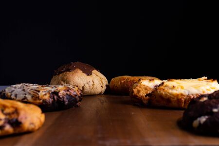 Different cookie cakes laying on a wooden board in front of a black backgroundの写真素材