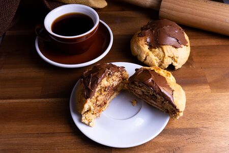 Delicious cookie cakes with chocolate with a cup of coffee on a wooden board with copy spaceの写真素材