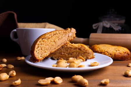 Fresh vegan cookie cakes with peanut butter, peanuts and a cup of coffee on a wooden board with copy spaceの写真素材