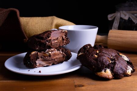 Delicious cookie cakes with chocolate with a cup of coffee on a wooden board with copy spaceの写真素材
