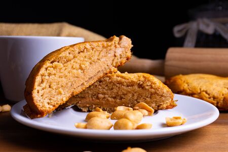 Fresh vegan cookie cakes with peanut butter, peanuts and a cup of coffee on a wooden board with copy spaceの写真素材