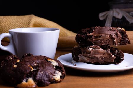 Delicious cookie cakes with chocolate with a cup of coffee on a wooden board with copy spaceの写真素材