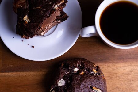 Delicious cookie cakes with chocolate with a cup of coffee on a wooden board with copy spaceの写真素材