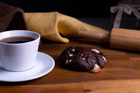 Delicious cookie cakes with chocolate with a cup of coffee on a wooden board with copy spaceの写真素材