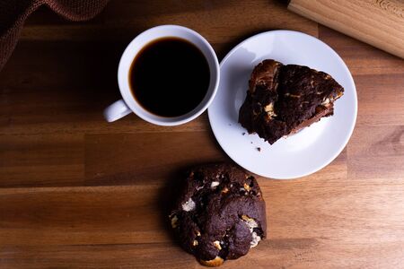 Delicious cookie cakes with chocolate with a cup of coffee on a wooden board with copy spaceの写真素材