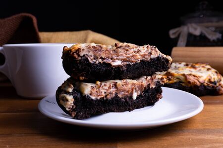 Delicious cookie cakes with chocolate and cheesecake with a cup of coffee on a wooden board with copy spaceの写真素材
