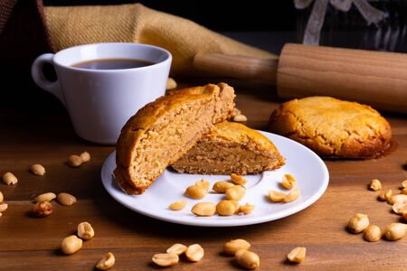 Fresh vegan cookie cakes with peanut butter, peanuts and a cup of coffee on a wooden board with copy spaceの写真素材