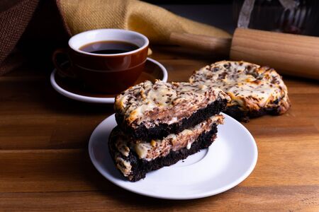 Delicious cookie cakes with chocolate and cheesecake with a cup of coffee on a wooden board with copy spaceの写真素材