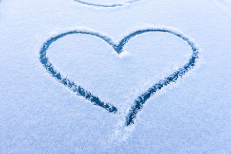 Heart love symbol on windscreen of car in snow. View of a snow car after a snowfall