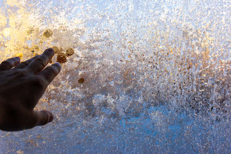 hand and fingers on a background of frozen glass. these are colored frosty patternsの写真素材