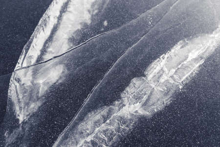 texture of stripes and cracks on a thick layer of ice of a lake or river. white cracks dark blue...