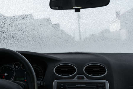 dashboard, rearview mirror and frosted car windscreen. Frosty patterns on the windshield of the car. view from inside the carの写真素材