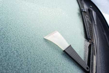 frosted car glass. Frosty patterns on a car windscreen. scraper for cleaning glass from iceの写真素材