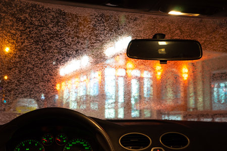 frosted car glass. snow covered car windshield. view from inside the car on the night cityの写真素材