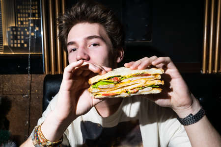 young man holding a sandwich in his hands.の写真素材