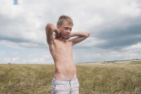 boy in shorts stands in the field. boy looks to the sky. dreamer guyの写真素材