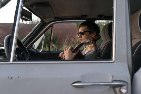 Two young man in the car. boy plays the guitar in the car. cheerful company of young people. journey...