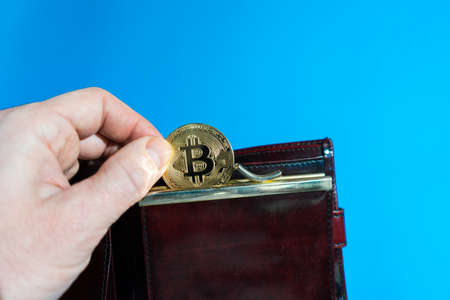 Bitcoin gold coin in leather wallet. bitcoin in the hands of a man.の写真素材