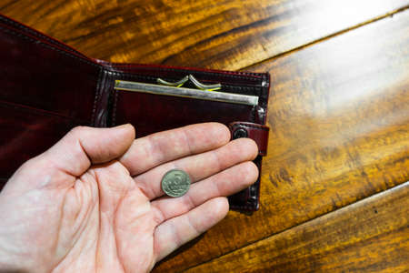The hand of an adult holds Russian five kopeks coin in the palm of his hand and opened wallet.