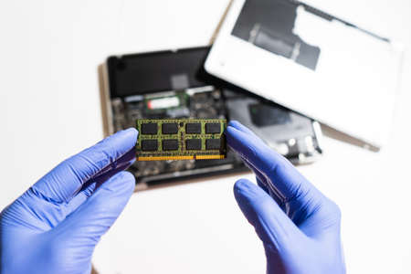 Service engineer installs new RAM memory chips to the laptop. Repairing and upgrading laptop...